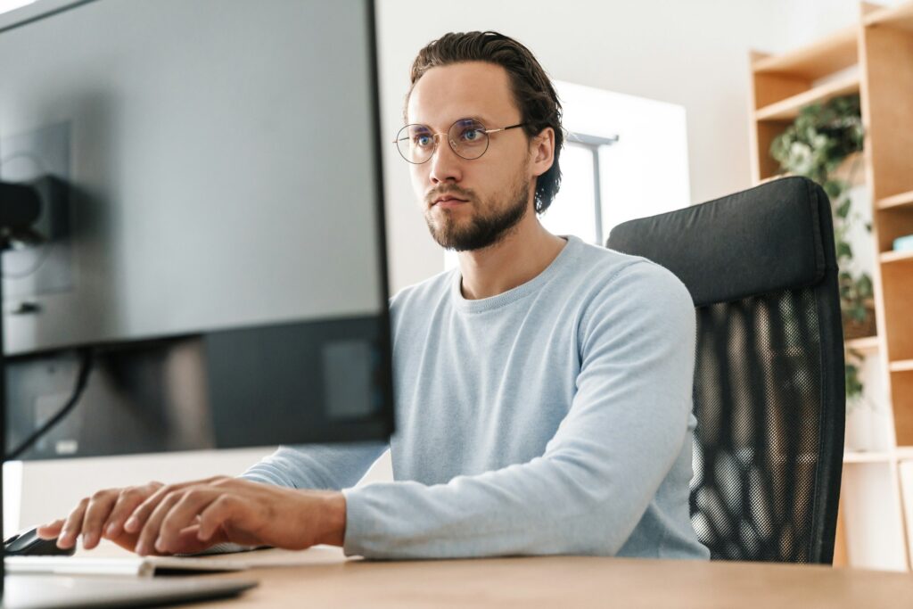 Image of focused unshaven programmer man working with computer